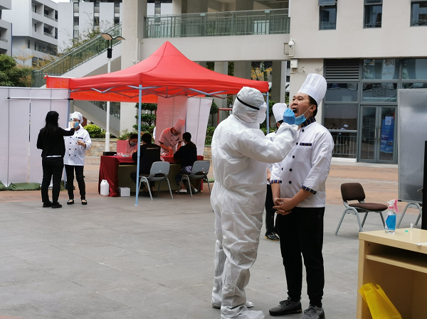 图为受检人员正在接受测温及采样
